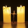 A cross standing between two lit candles