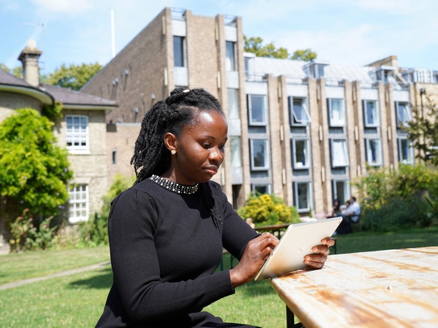 A postgraduate student working outside on a tablet computer in Darwin College