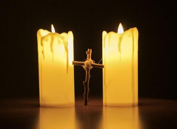 A cross standing between two lit candles