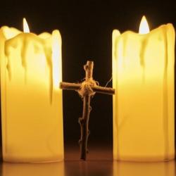 A cross standing between two lit candles